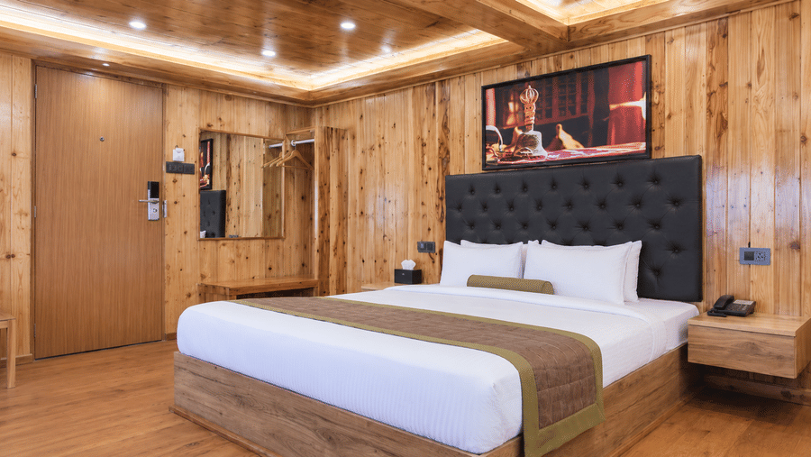 Guest room at Valmere Magnolia Boutique Hotel & Spa, Pelling with a bed, a dark headboard, a wall-mounted TV, a framed photo above it, and a wardrobe mirror.
