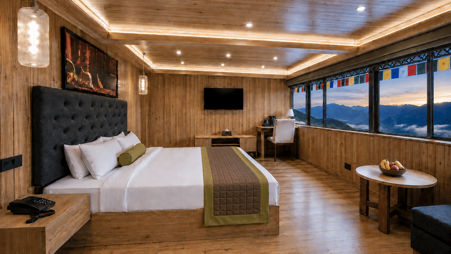 Guest room at Valmere Magnolia Boutique Hotel & Spa, Pelling with a bed, a dark headboard, and a window strung with prayer flags overlooking mountains at dusk.