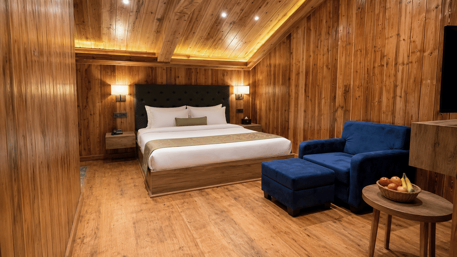 Attic Suite bedroom at Valmere Magnolia Boutique Hotel & Spa, Pelling with a sloped wood ceiling, a bed, a navy armchair, and a fruit bowl on a side table.