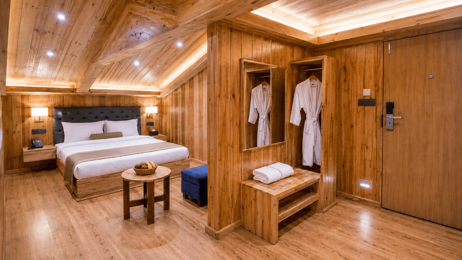 Attic Suite at Valmere Magnolia Boutique Hotel & Spa, Pelling with a sloped wood ceiling, a bed, a mirrored wardrobe with robes, and folded towels on a bench.