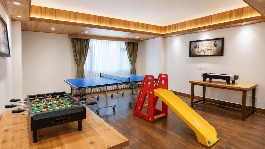 Indoor game room at Valmere Magnolia Boutique Hotel & Spa, Pelling with a table tennis table, foosball table, air hockey table, and a children's slide.
