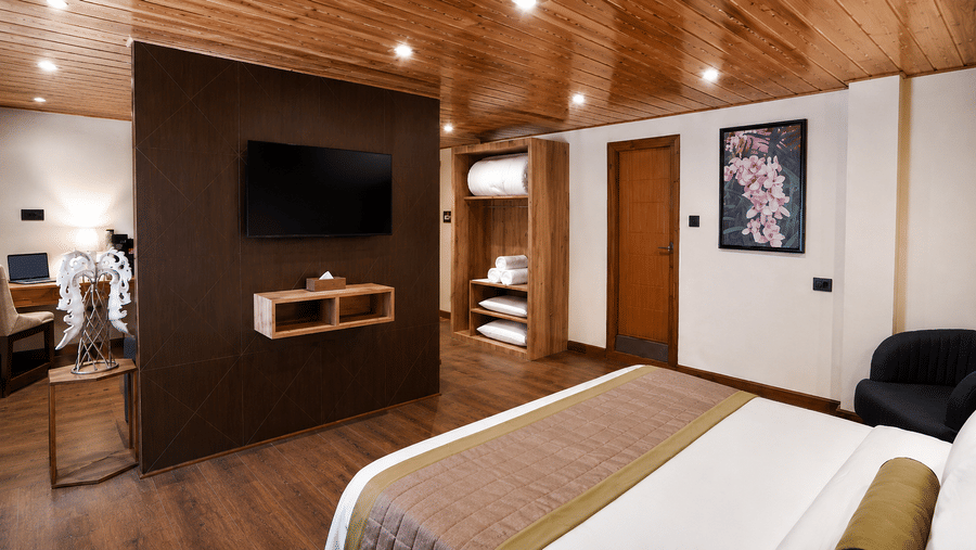 King Suite at Valmere Magnolia Boutique Hotel & Spa, Pelling with a wall-mounted TV, an open wardrobe with folded towels, a wooden door, and a framed floral print.