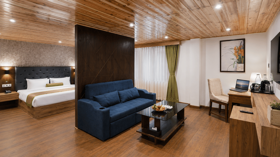 King Suite at Valmere Magnolia Boutique Hotel & Spa, Pelling with a partition wall, navy sofa, glass coffee table, a work desk with laptop, and a tea/coffee station.
