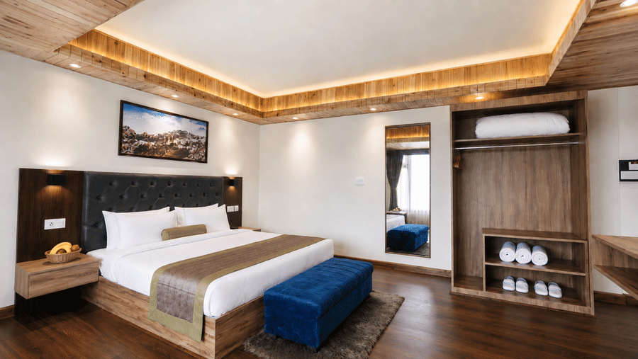 Guest room at Valmere Magnolia Boutique Hotel & Spa, Pelling with a bed, a full-length mirror, and an open wardrobe with folded towels and slippers.