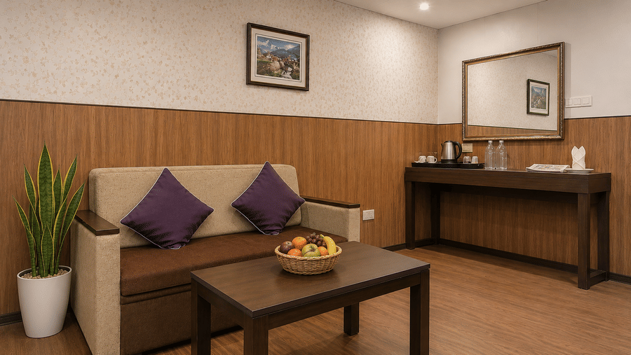 Living room area at Valmere Thistle Boutique Hotel, Darjeeling with a beige sofa, purple cushions, a snake plant, and a console table with a kettle.