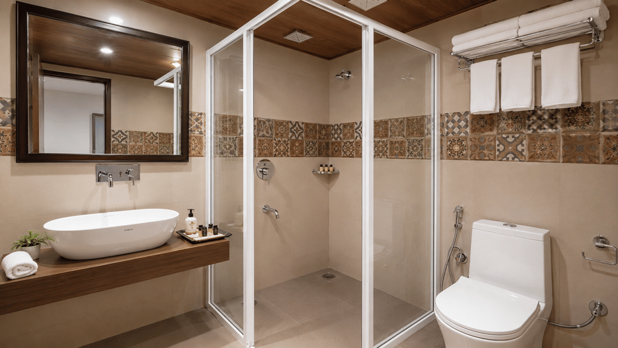 Bathroom at Valmere Thistle Boutique Hotel, Darjeeling featuring a patterned-tile walk-in shower, oval vanity sink, and folded towels on a rack.