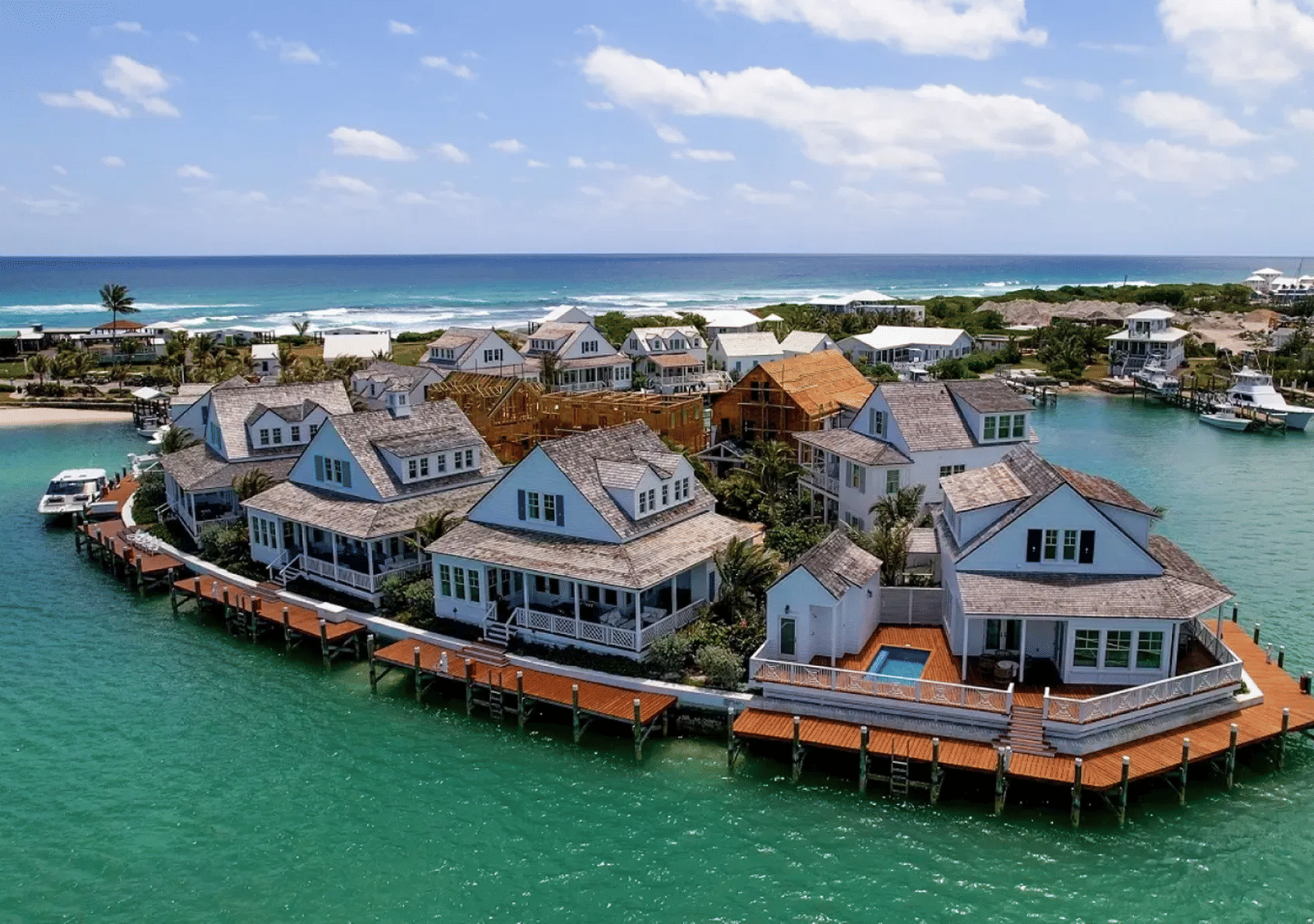 A bird's eye view of several villas overlooking the sea water with a green tint in front of it.