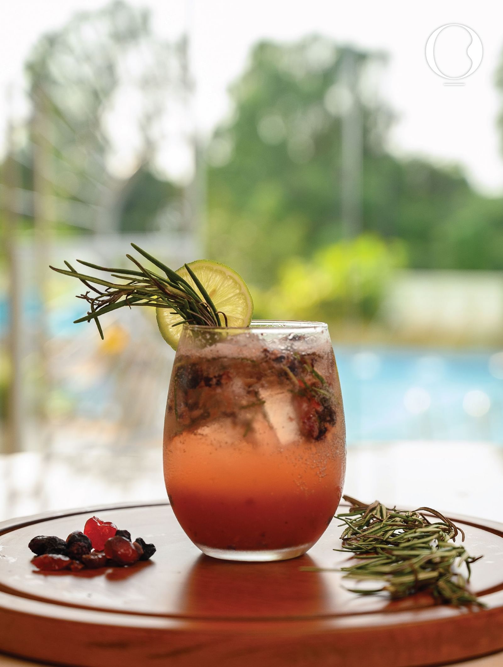 A close up shot of a refreshing glass of a cocktail with a backdrop of a swimming pool at Miros Hotels.