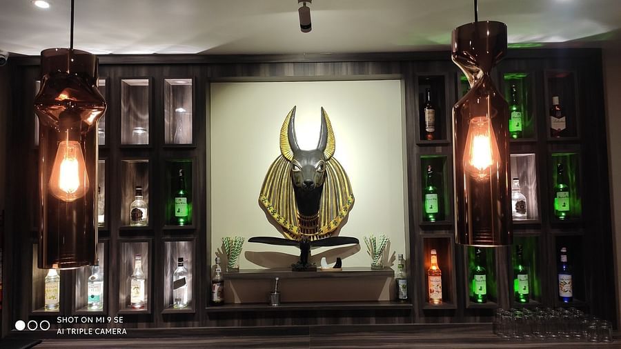 A dark, atmospheric display cabinet featuring a central golden statue surrounded by decorative elements and warm, glowing lights - Sea Hills Hotels, Sri Vijaya Puram (Port Blair)