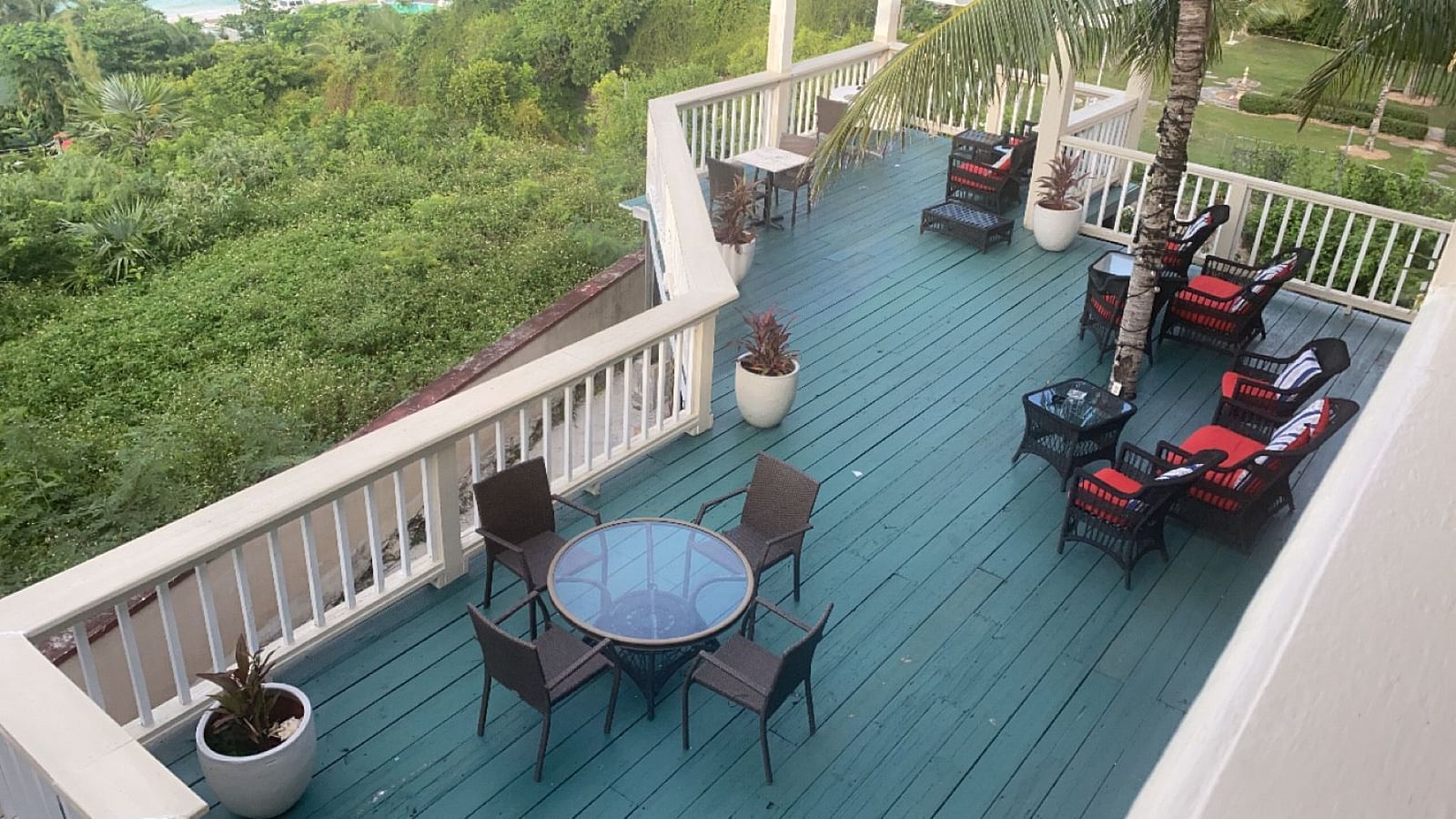Elevated deck with chairs and tables overlooking lush greenery | A Stone's Throw Away