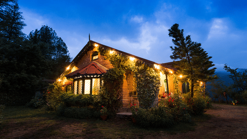Exterior of a bungalow with dim lights during sunset - Ramgarh Bungalows, Nainital.