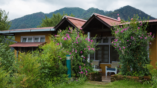 Exterior of a bungalow surrounded with plants and flowers - Ramgarh Bungalows, Nainital.