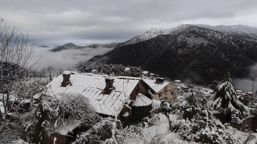Bird's eye view of snow covered bungalows enveloped by mountains - Ramgarh Bungalows, Nainital.