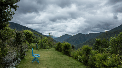 Scenic view of the Kumaon landscape filled with lush greenery and a chair - Ramgarh Bungalows, Nainital.