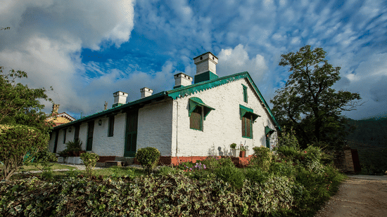 Facade of the Ramgarh Bungalows by Neemrana Hotels surrounded by plants on a bright sunny day.