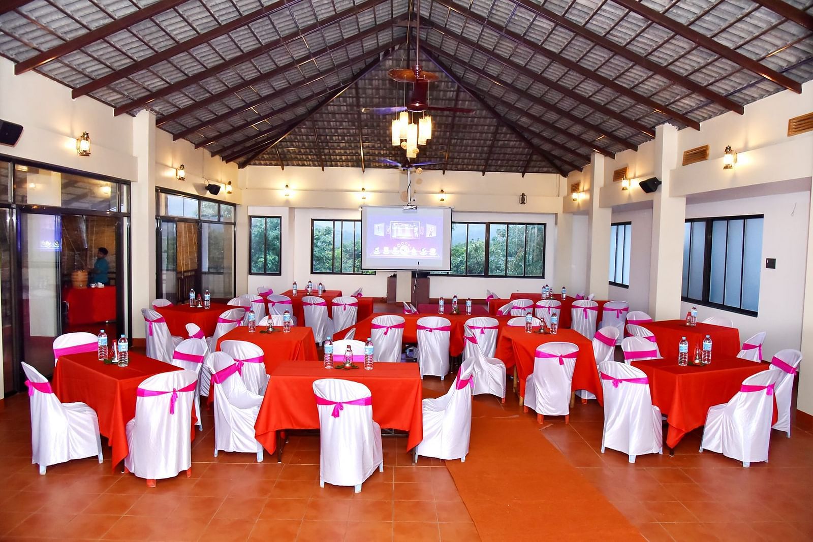 A banquet hall at Forest Escapes Koyna is elegantly set up with draped chairs and round tables, possibly for an event.