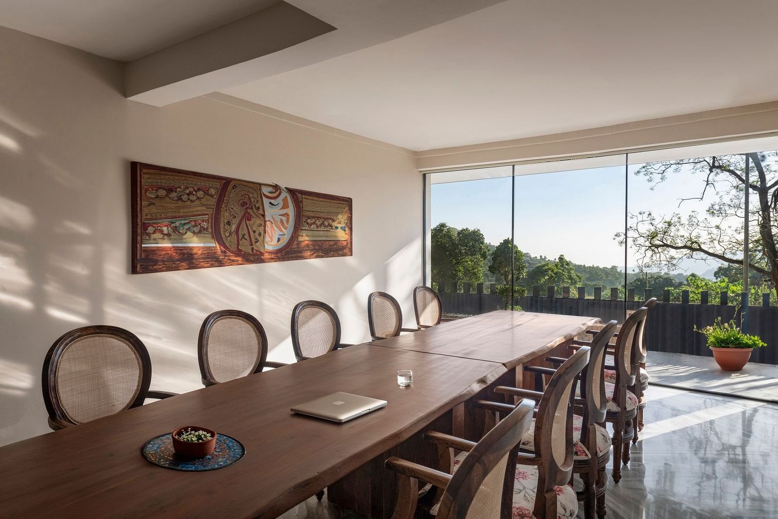 A meeting room with a long table in front of a glass door opening to a lush green garden - The Samai, Bhimtal