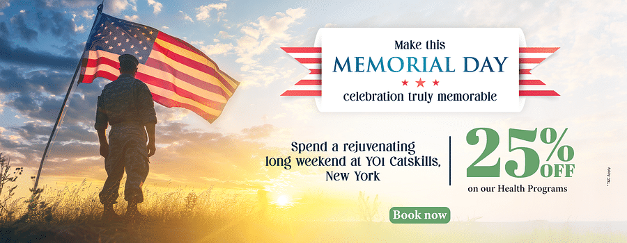 A soldier standing in front of the US flag as the sun is rising from the horizon as the text says - Make this Memorial Day celebration truly memorable. 25% off on our health programs at YO1 Longevity & Health Resorts
