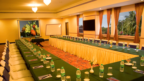 A conference room at the best resort in Bangalore, with long tables, chairs, water glasses, and notepads | Ramanashree California Resort