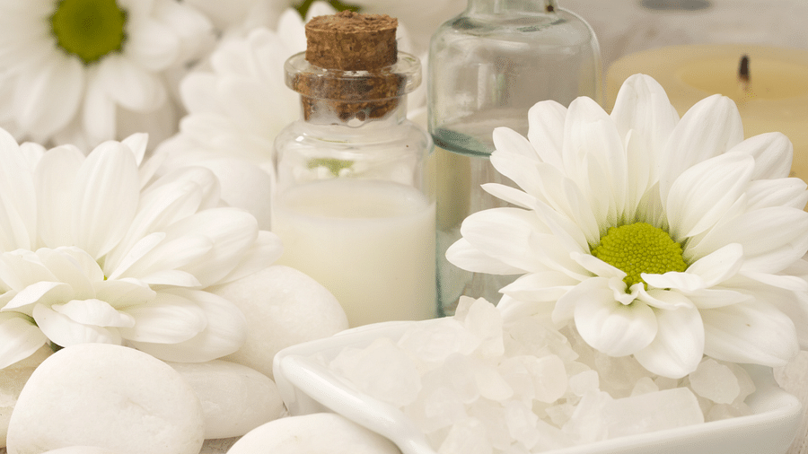 Various kinds of oils and liquids kept on a table of massage centre with flowers