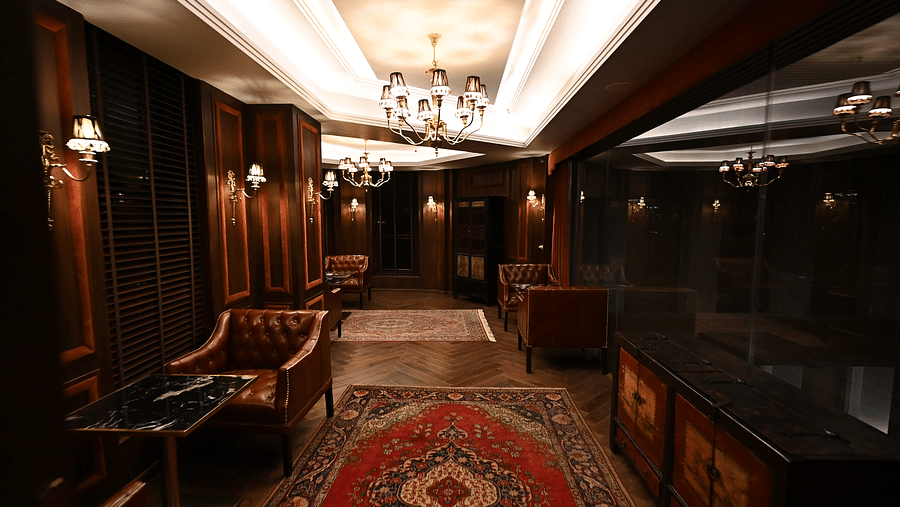 Elegant wood-panelled lounge with leather Chesterfield chairs, crystal chandeliers, and Persian rugs at The Manor Wellness & Sports Hotel