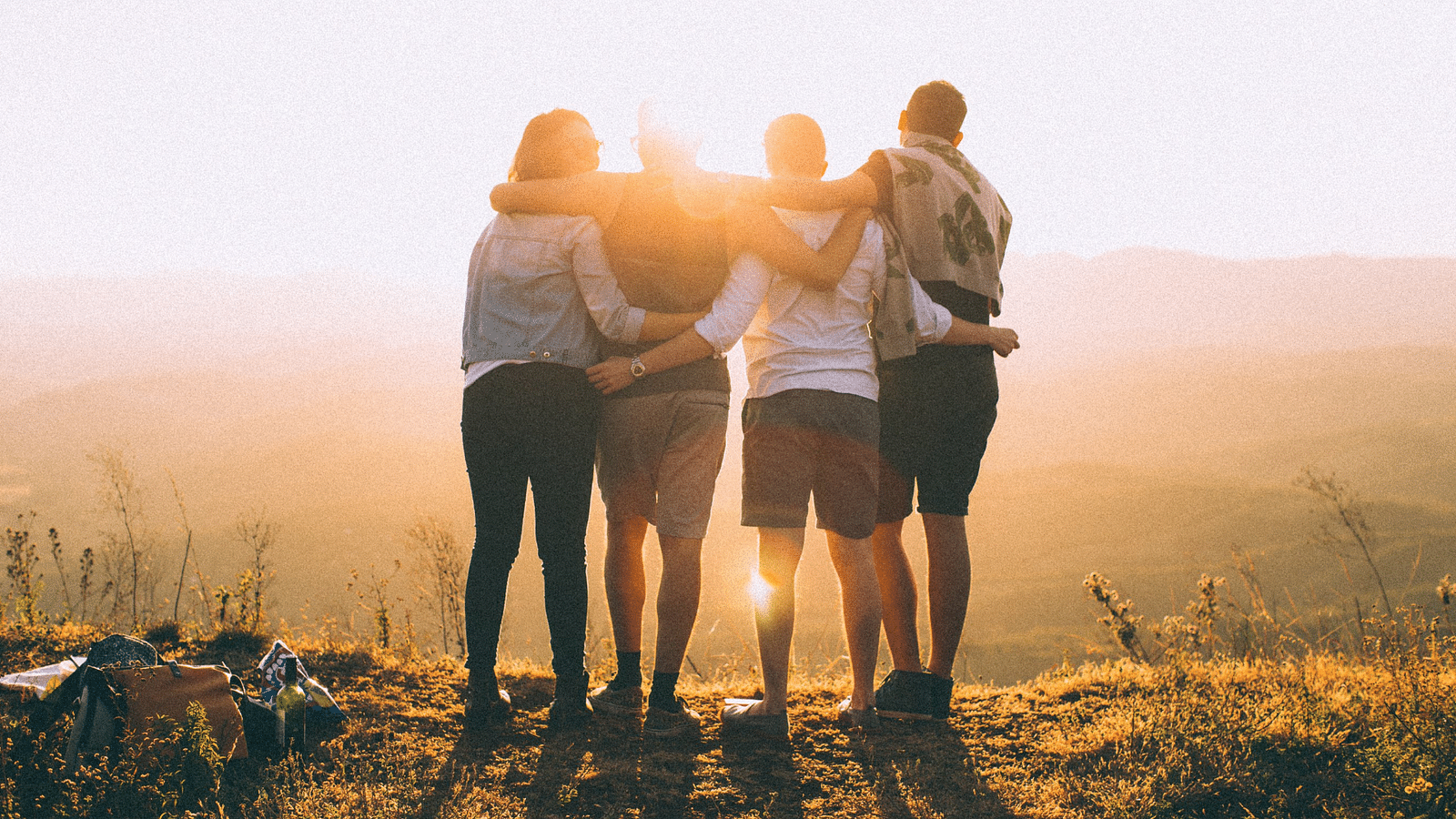 an image of Friends watching the sunset together holding each other