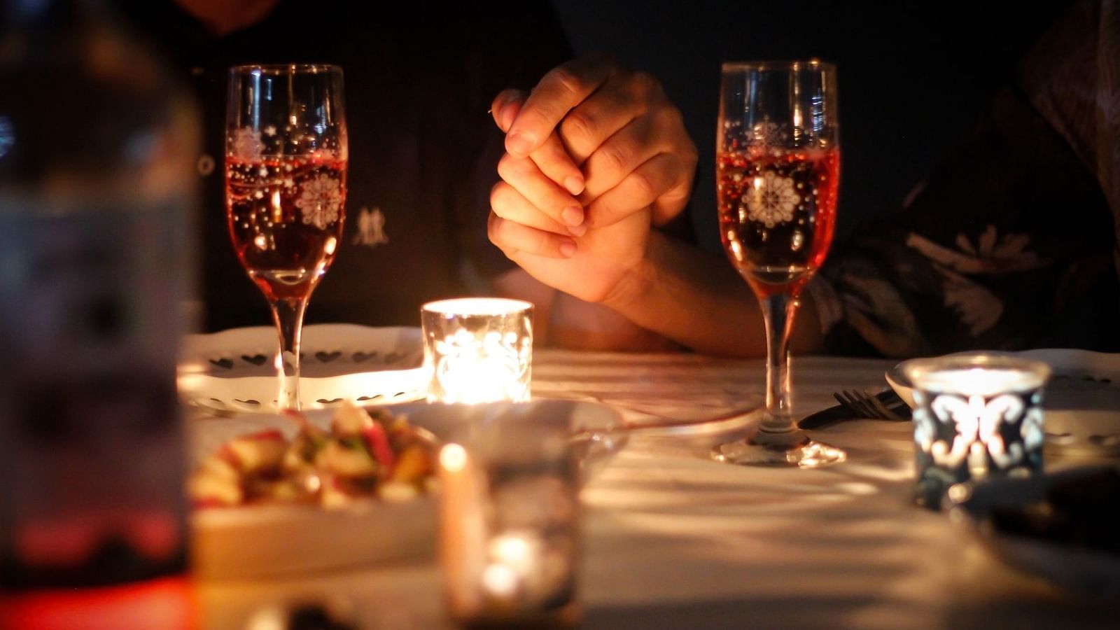 an image of a couple holding hands on a romantic candlelight dinner