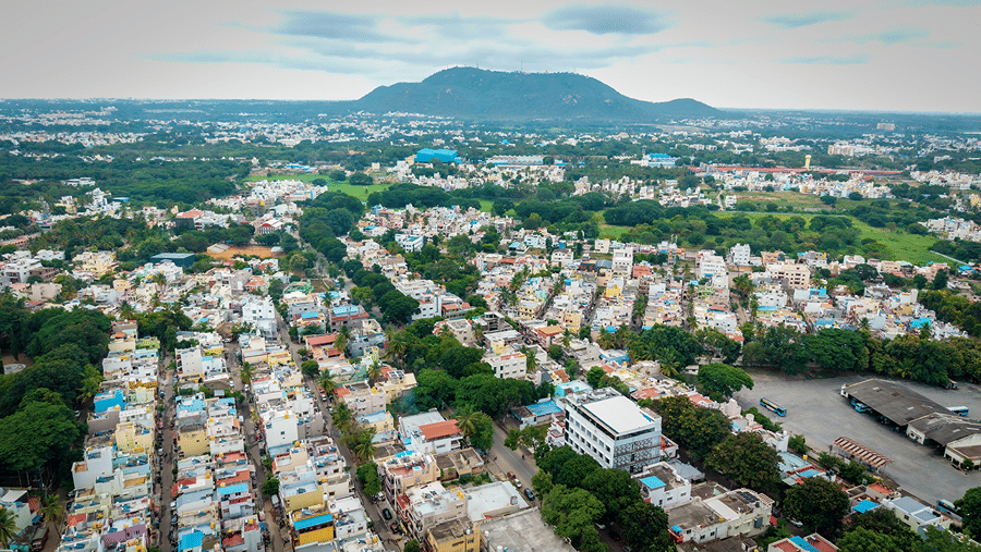 Elevated view of the city showing residential buildings, tree-lined areas and hills in the distance.