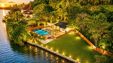 Aerial view of Lake View Family Cottage with Private Pool at Fragrant Nature Kollam, showing the pool deck and lakefront setting at sunset