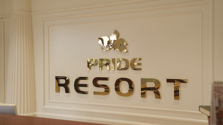 A close-up of a wall displaying PRIDE RESORT in large, golden, stylised lettering, indicating the establishments name in Rajkot.