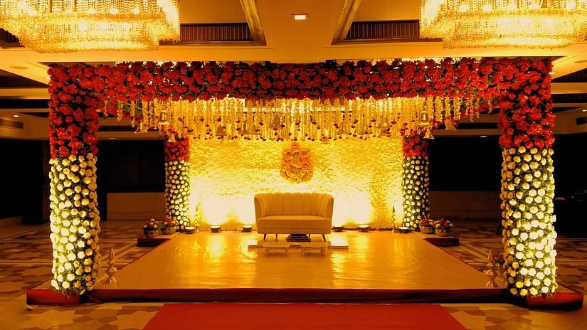 A close view of the stage of a grand wedding setup at Pride Plaza Ahmedabad, featuring a beautifully decorated backdrop with floral arrangements, a plush sofa, and a red carpet leading to the stage.