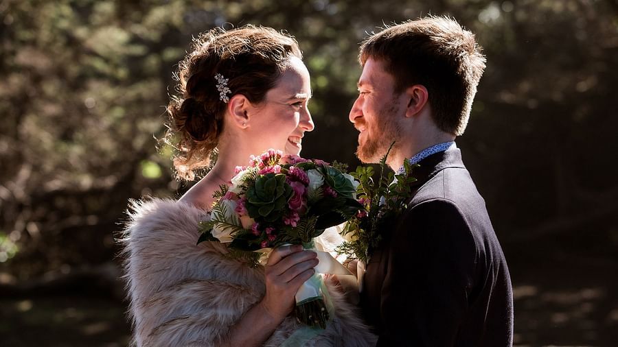 Bride in a fur stole holding a bouquet while gazing into her groom’s eyes