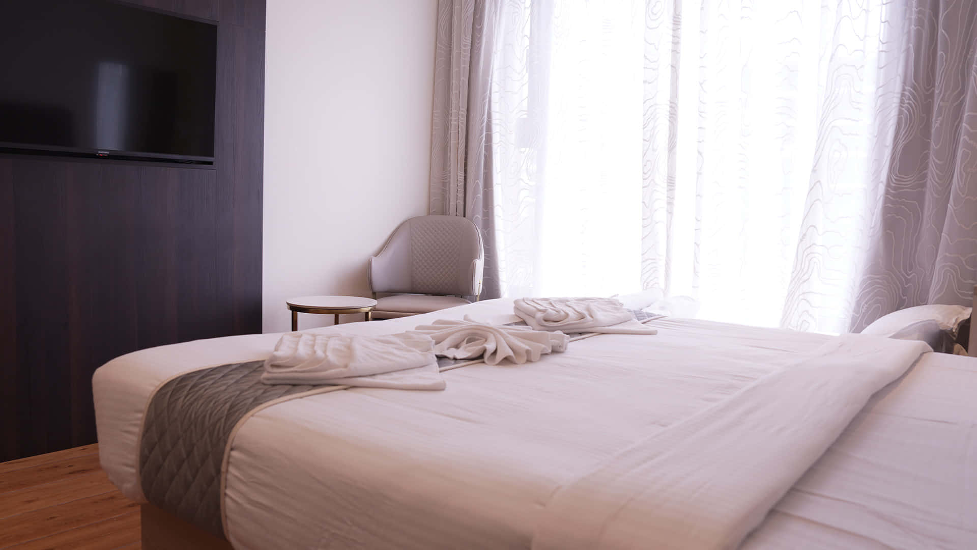 Guest room at Hotel Ritvi's Elite set up for three, beds side by side facing a wall-mounted television