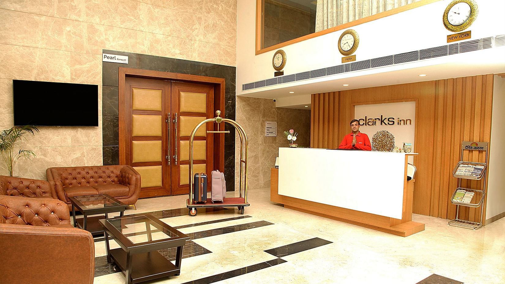 Lobby of our hotel in Aligarh featuring the reception desk and a TV on the wall along with the seating area