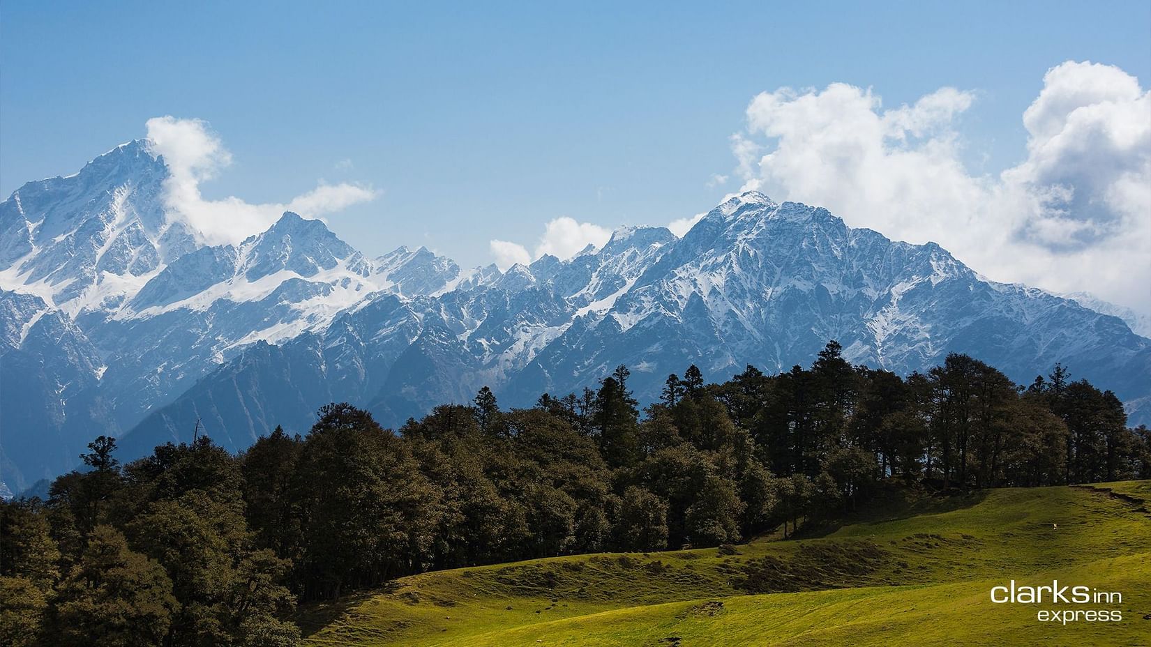 A landscape view of mountains with their heads covered with clouds and the lush greenery spread across