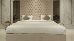 A king-sized bed at Pride Resort, Rajkot featuring a tufted headboard in a contemporary hotel room, decorated with neutral tones