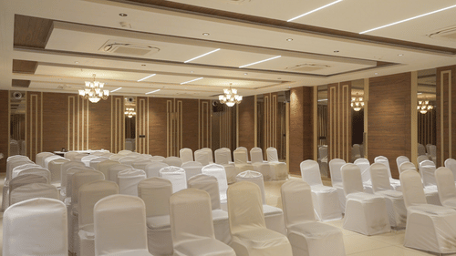 An expansive, elegant event space in Pride Resort, Rajkot, completely set up with countless white chairs meticulously arranged in rows, ready to host a large gathering or presentation
