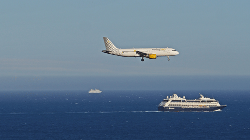 A ship sailing in water and plane flying
