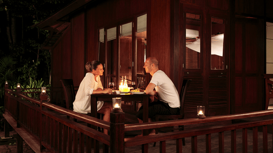 A couple romantically looking at each other and enjoying a meal at the in-house restaurant of Barefoot at Havelock. The resort provides numerous packages in Andaman, including a romance special package.