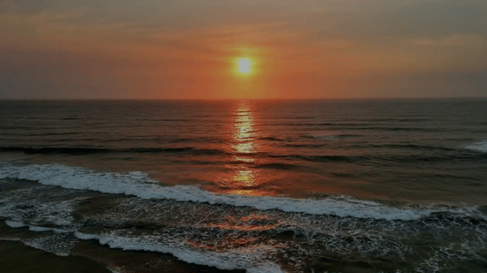 Sunset over the ocean with gentle waves reflecting golden hues, captured for Stone Wood Hotels & Resorts.