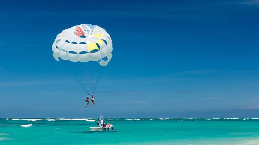 A couple parasiling above clear waters