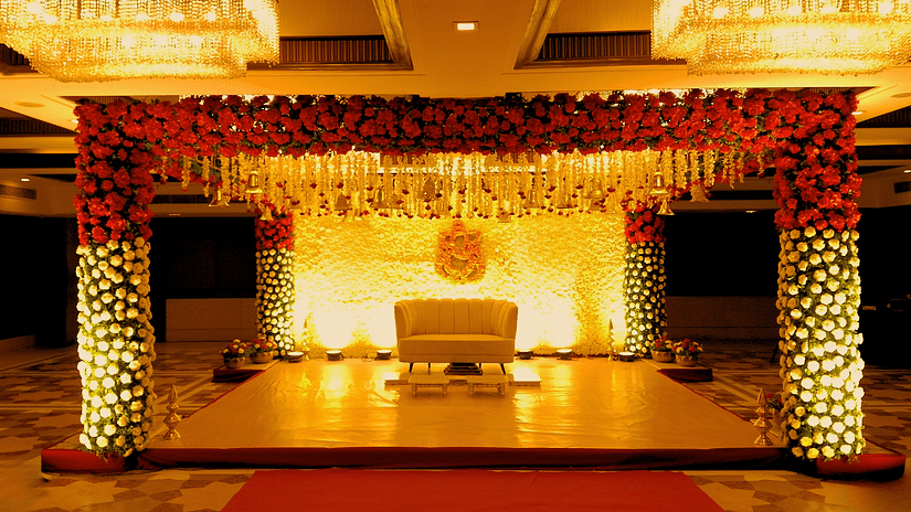 A close view of the stage of a grand wedding setup at Pride Plaza Ahmedabad, featuring a beautifully decorated backdrop with floral arrangements, a plush sofa, and a red carpet leading to the stage.
