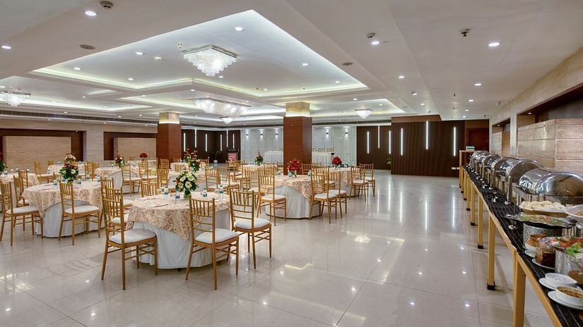 Banquet hall at Sapna Clarks Inn (or Clarks Inn). Round tables set for a meal, buffet setup on the side.  Ideal for weddings, conferences, or events.
