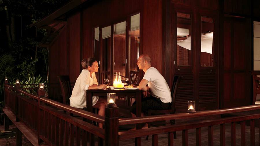 A couple romantically looking at each other and enjoying a meal at the in-house restaurant of Barefoot at Havelock. The resort provides numerous packages in Andaman, including a romance special package.