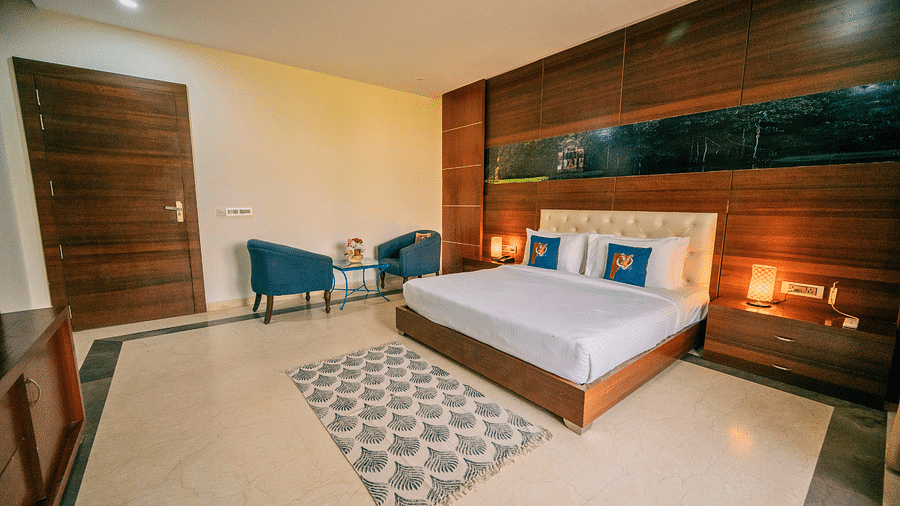 Well-appointed bedroom with a king-size bed, a patterned rug, comfortable armchairs, and a modern design with warm lighting - Clarks Safari, Ranthambore