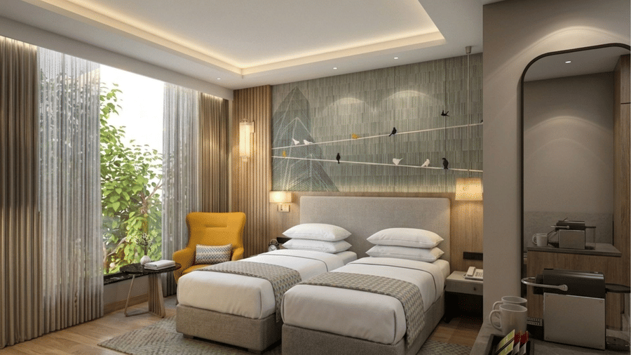 A Deluxe Room at KPG Sarovar Portico, Raj Nagar Extension, Ghaziabad, featuring twin beds, a recessed ceiling with cove lighting, and a tall window overlooking greenery.