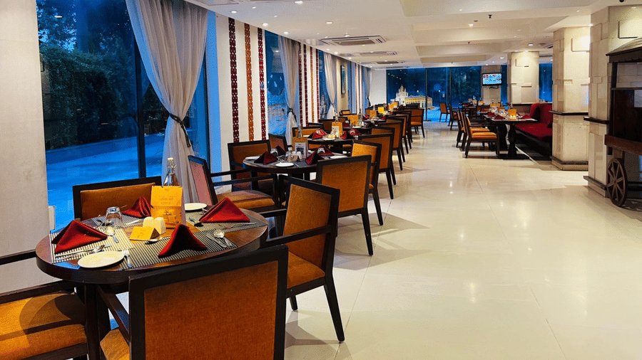 A restaurant interior with multiple tables and chairs arranged for guests.