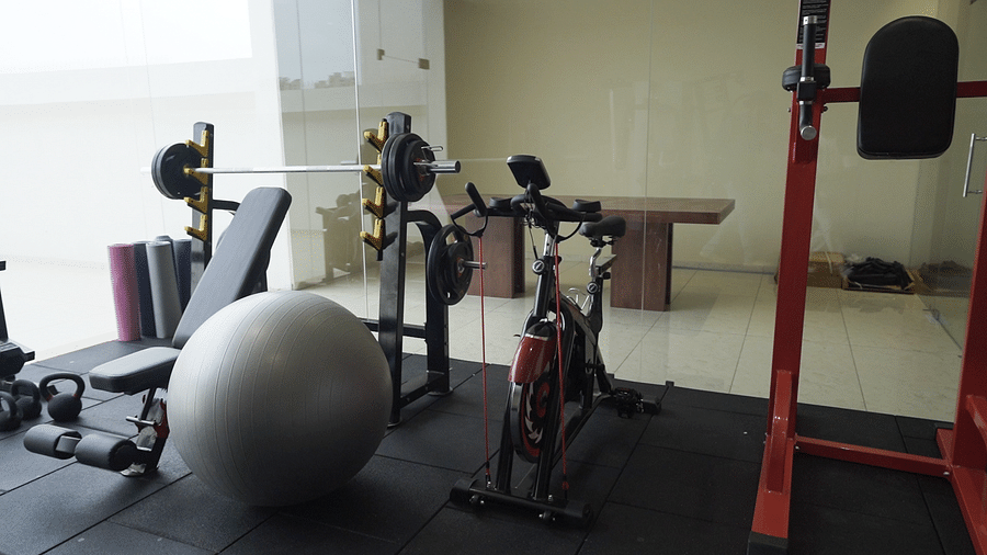 A hotel fitness centre at Pride Resort, Rajkot featuring diverse exercise equipment, including weights, a bench, and a large grey stability ball.