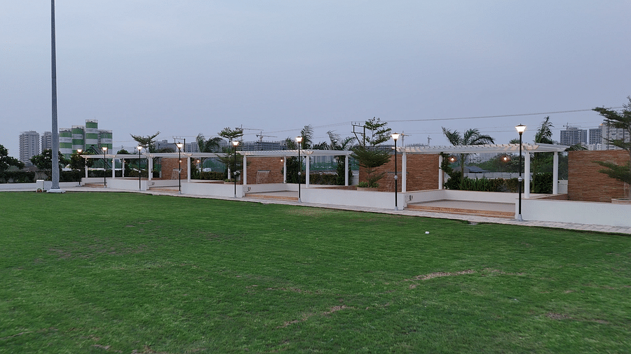 Overview of an expansive lawn with tall halogen lights put up in the perimeter featuring a small water fountain - Pride Resort, Rajkot