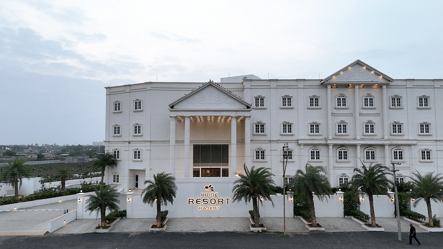 Front view image of the facade of the resort with white coloured exterior and a tall entrance - Pride Resort, Rajkot